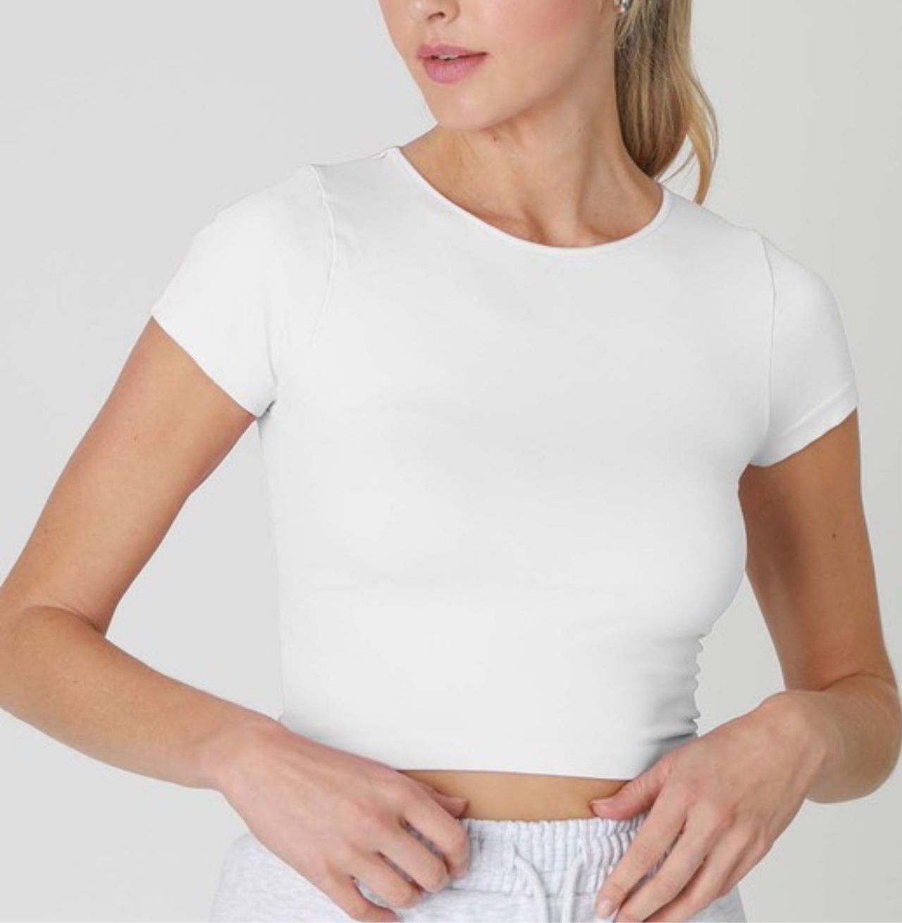 Front view of NIKIBIKI Jersey Solid Baby Tee in white – fitted cropped crew neck t-shirt with short sleeves, styled with casual joggers.”